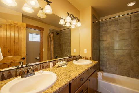 bathroom with tiling and warm lighting above a double sink. 
