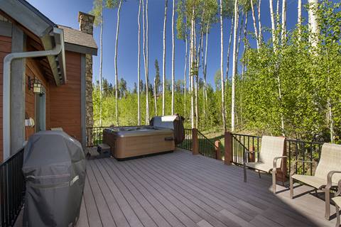 Large patio with dark brown paneling and aspen trees in the background. 