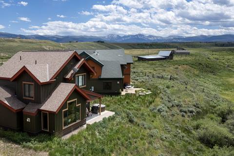 Aerial view of mountain home with fields and mountains in the background. 
