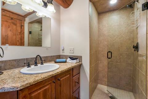 Bathroom with granite countertop vanity, single sink, and glass-enclosed tiled walk-in shower.