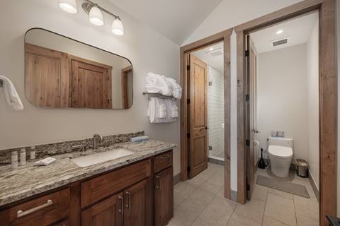 Bathroom with granite vanity, double sinks, and separate shower and toilet areas.