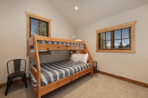 Bedroom with wooden bunk bed, striped bedding, and carpeted floor.