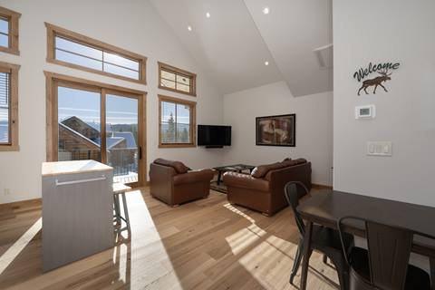 Bright kitchen with stainless steel appliances, wooden cabinetry, and an island with seating for two.