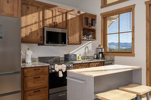 Open layout showing kitchen, island, living area with leather sofas, and sliding doors to balcony.