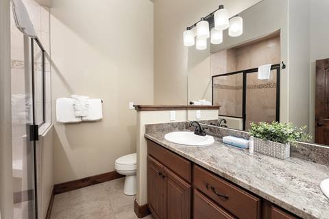 Bathroom with granite counter, single sink, and glass-enclosed shower.