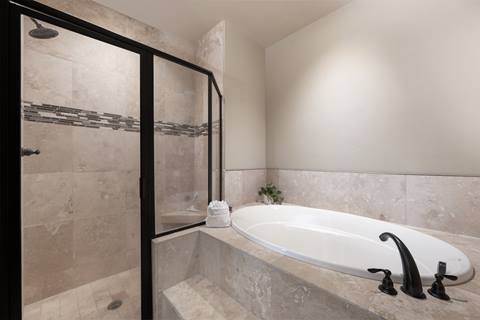 Bathroom with soaking tub, glass shower, and tile surround.