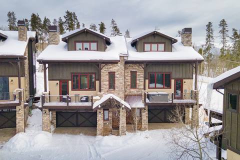 Winter exterior view of Mountain Terrace townhomes surrounded by snow, with balconies and stonework detail.