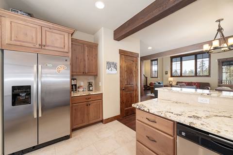 Kitchen view with stainless steel refrigerator, granite counters, and wooden cabinetry.