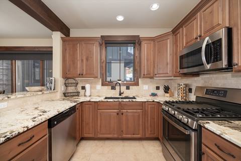 Fully equipped kitchen with granite countertops, gas range, microwave, and ample storage.