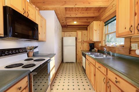 Galley kitchen with wood cabinets, electric stove, and green countertops.