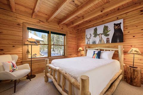 Bedroom with rustic log bed frame, animal-themed artwork, and wood-paneled walls.