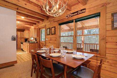 Wood-furnished dining room with wooden walls and warm lighting. 