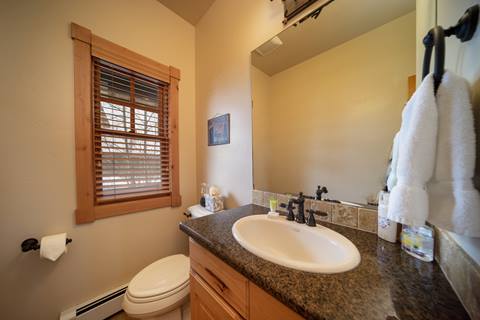 Half bath with granite vanity, under-mount sink, framed mirror, and window with blinds.