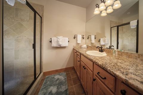 Full bathroom with a glass-enclosed shower, granite countertop, and warm wood cabinetry.
