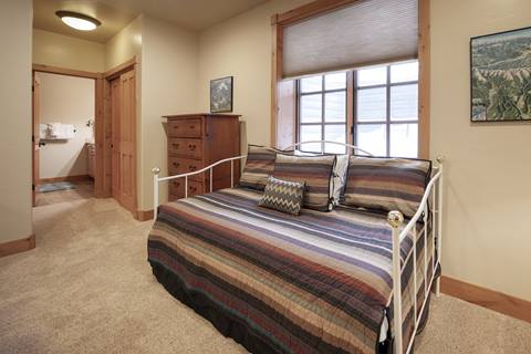Cozy guest room with a striped daybed and dresser, opening to a full bathroom.