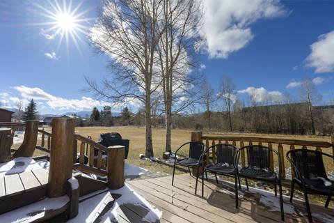 Outdoor deck with seating area and mountain views across a large open meadow.