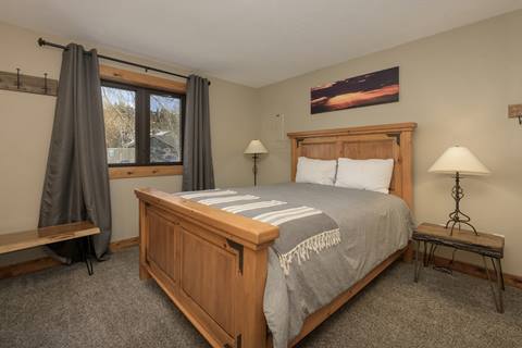 Bedroom with queen bed, gray bedding, and rustic wood furnishings.