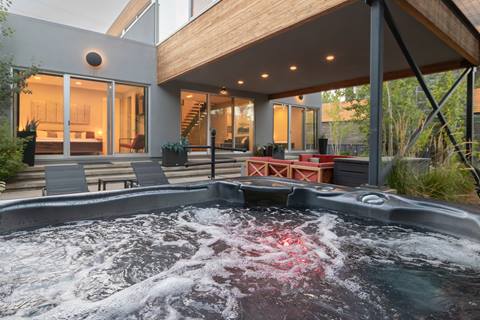 Outdoor hot tub bubbling with view of patio seating area and bedroom.
