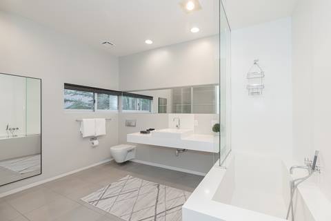 Spacious bathroom with floating sink, bathtub, and large mirror.