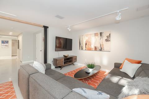 Lounge with sectional sofa, wall-mounted TV, coffee table, and modern artwork.