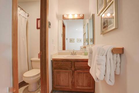 Bathroom with wooden vanity, mirror, and shower-tub combination.