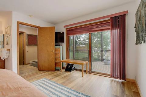Bedroom with sliding glass door to deck, small bench, and dresser with mounted TV.