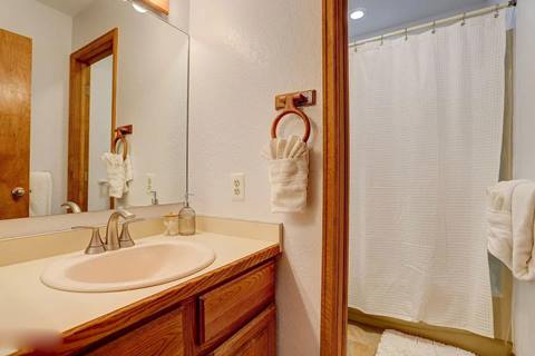 Bathroom with large mirror, single vanity, and shower with white curtain.