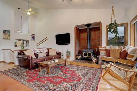 Cozy living room with leather sofa, wood stove fireplace, flat-screen TV, and red area rug.