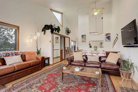 Spacious living room with tall ceilings, two leather sofas, and large windows providing natural light.