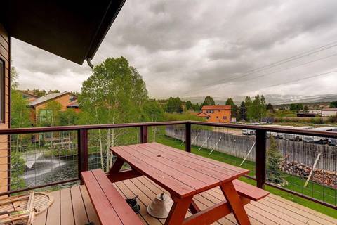 Outdoor deck with picnic table overlooking neighborhood and mountain views in the distance.