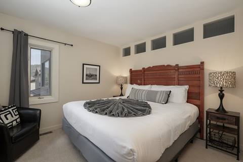 Bedroom with a king bed, wooden headboard, and armchair by the window.