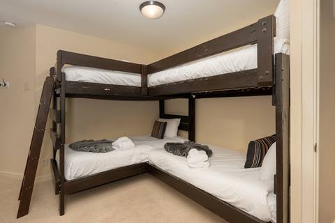 Bunk bedroom with two sets of wooden bunk beds and white bedding.
