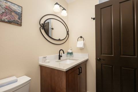 Bathroom with wood vanity, oval mirror, and light fixture above.