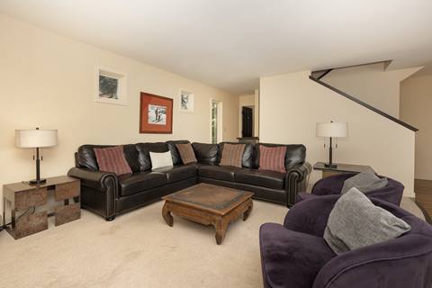 Living room with sectional sofa, purple chairs, and coffee table.