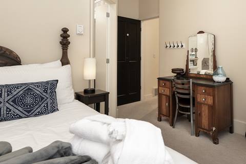 Cozy bedroom with white bedding, wooden vanity, and vintage-style décor.