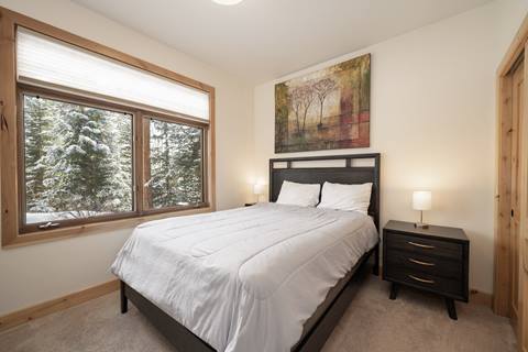 Bedroom with a queen bed, large window, and forest views.