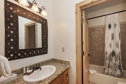 Bathroom with granite countertop, rustic mirror, and a shower-tub combo.