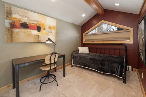 Small loft room with a desk and single daybed against angled ceiling.