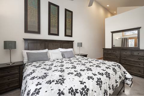 Master bedroom with a king bed, dark wood furniture, and tall artwork.