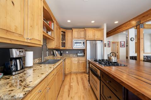 Kitchen with granite countertops, stainless steel appliances, and wooden cabinets, viewed from a side angle.