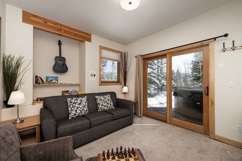 Cozy sitting area with a sofa, armchairs, and a wall-mounted guitar.