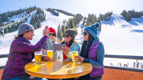 Women sitting outside in front of Winter Park Ski Resort with beer