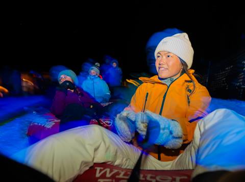family enjoying night snow tubing at winter park resort