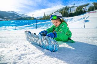 Child putting on a snowboard at Winter Park Resort