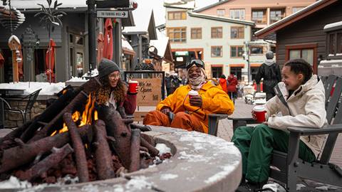 Family sipping hot coca by the fire at winter park resort