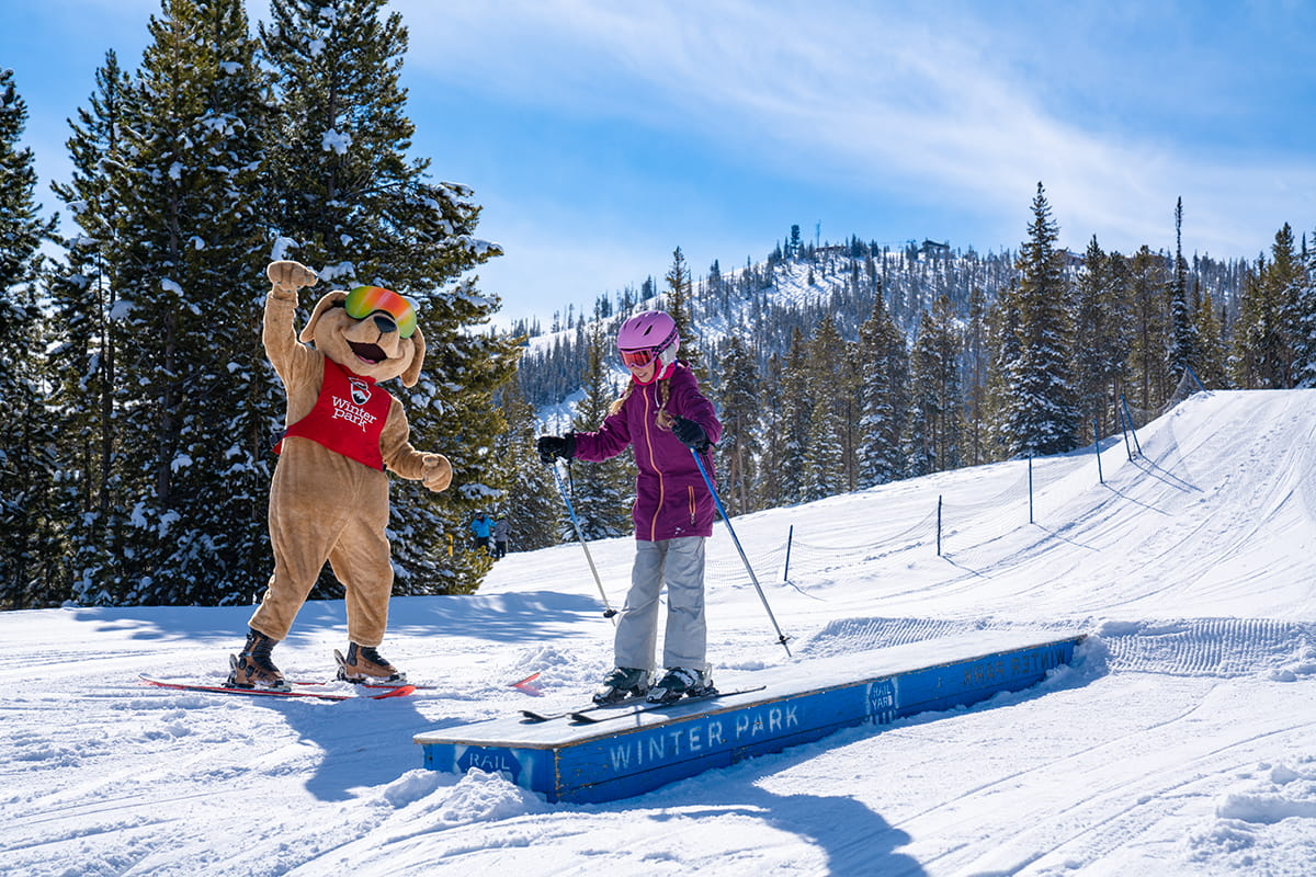 Child skis with Parry the Mascot at Winter Park Resort
